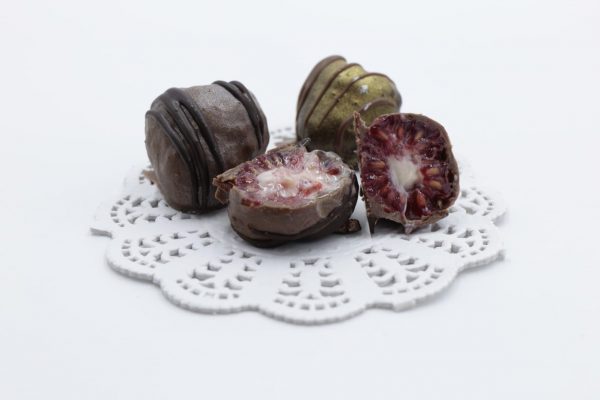 Frambuesa rellena de crema de frutos rojos bañada en chocolate belga y chocolate con leche